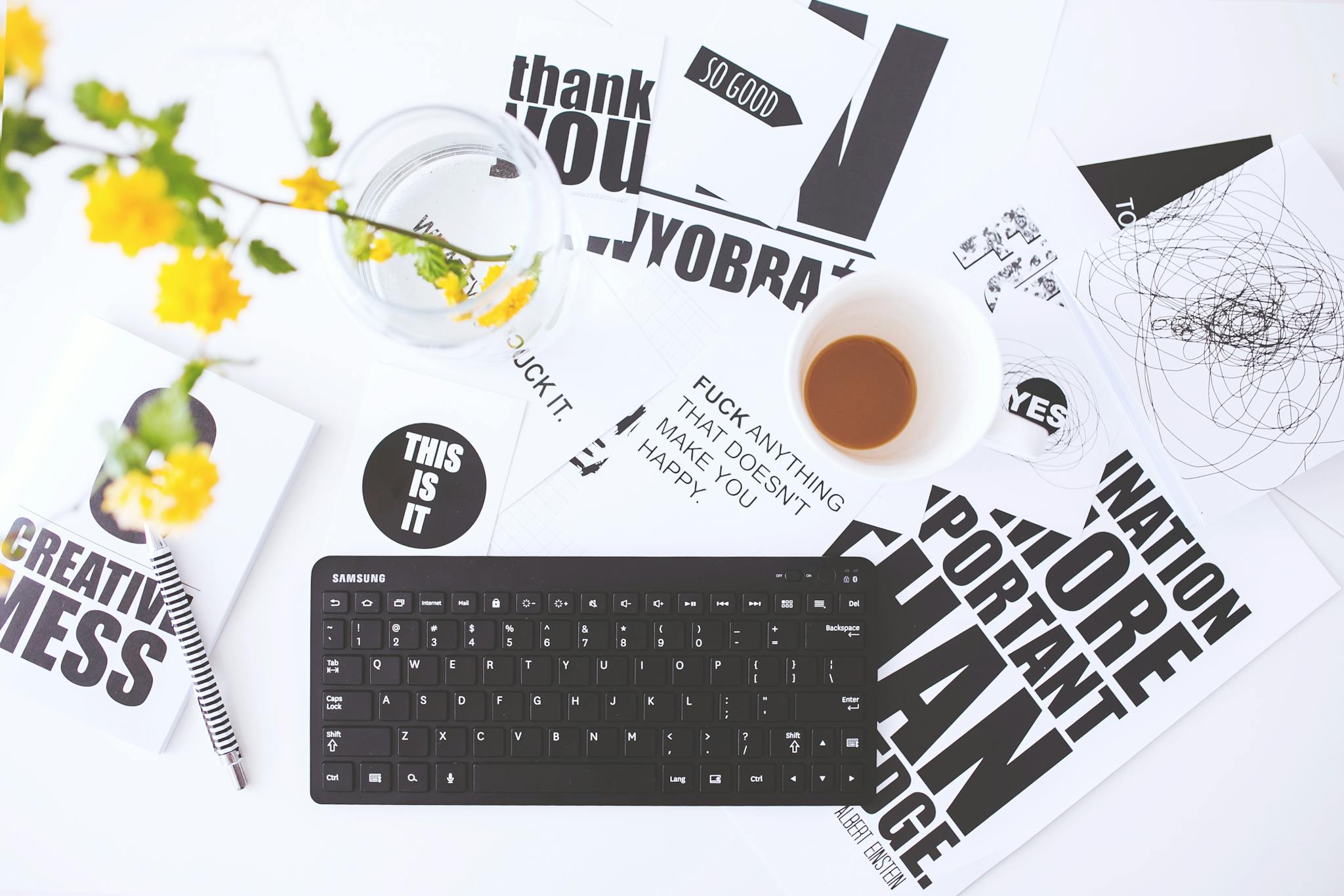 Overhead view of a creative workspace with scattered papers, coffee cup, and keyboard.